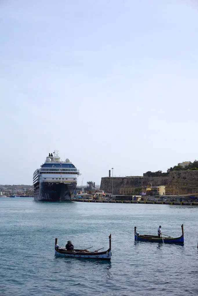 Traditional Maltese boats in the Grand Harbour with a cruise ship behind