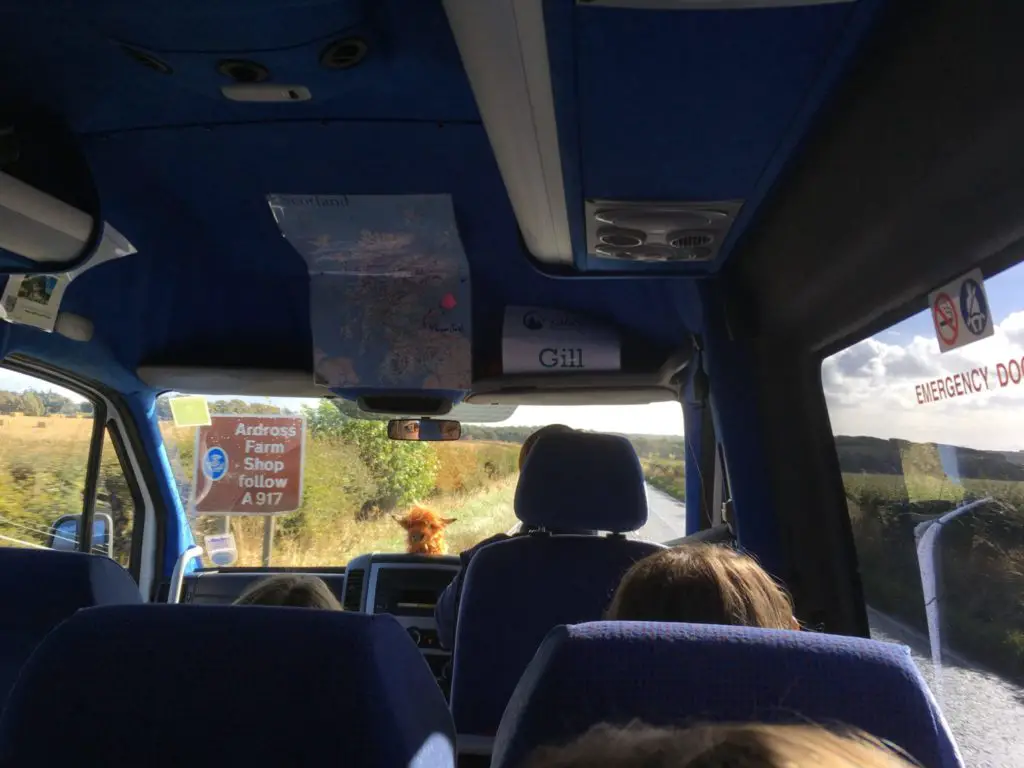 Rabbie's tour bus in Scotland with driver guide Gill at the wheel and Kevin the Coo on the dashboard