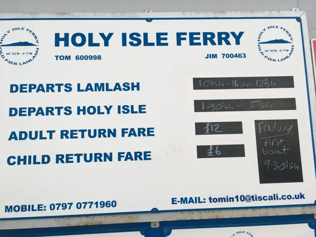 Sign for the Holy Isle ferry in Arran Scotland detailing departure times and costs