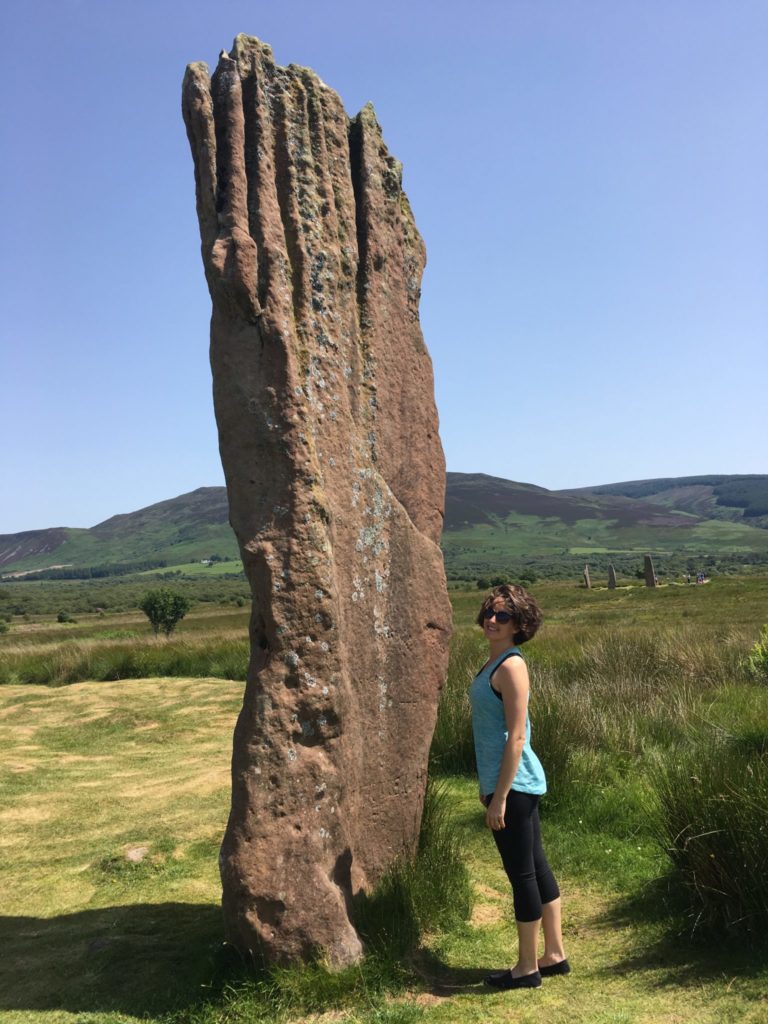 Amanda Walkins standing beside a standing stone at Machrie on the Isle of Arran