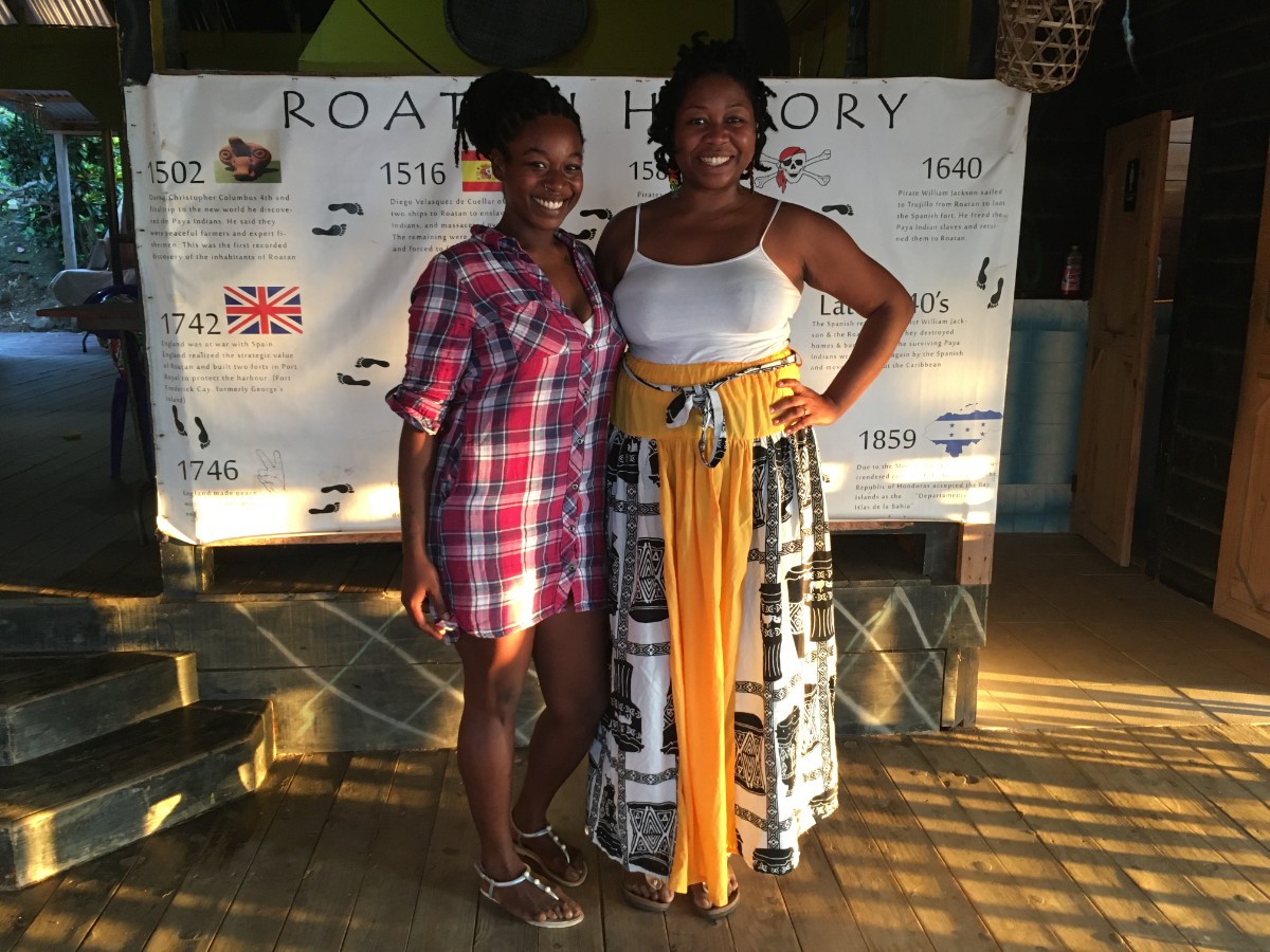 Nora and Audrey Flores of the Garifuna Cultural Center in Roatan (formerly the Flamingo Cultural Center) standing in front of the history of Roatan timeline