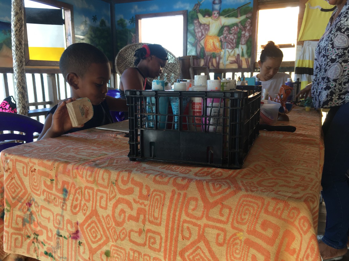 Women and kids painting at a table in Punta Gorda Roatan